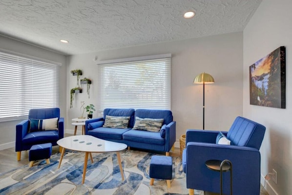 A living room with a blue sofa set, a white coffee table, and a floor lamp.
