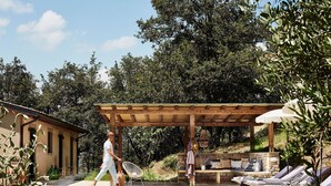 A pool area with a pergola, lounge chairs, and a stone bench.