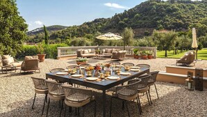 An outdoor dining area with a table set for six, surrounded by wicker chairs, a sofa, and an umbrella. - Villa Annabelle - Six Bedroom Villa, Sleeps 18 (Lucca)