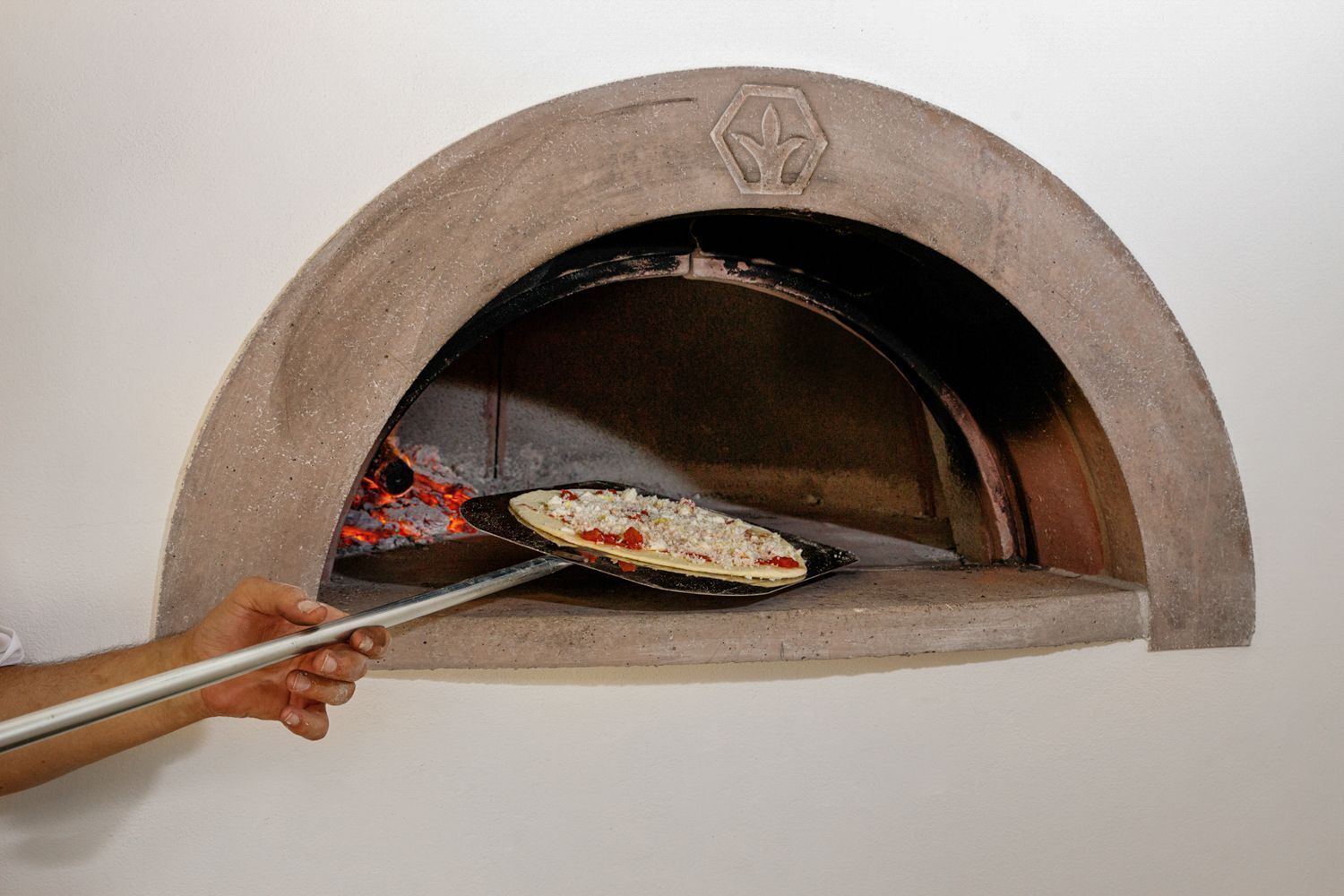 A person placing a pizza into a brick oven.