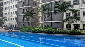 Un hôtel moderne doté d’une piscine, de nombreux balcons et d’une végétation luxuriante.