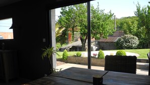 A room with a large window, a wooden table, and a chair. - Gîte de Campagne (Widehem)