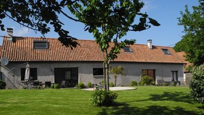 A house with a tiled roof, a patio with outdoor furniture, and a well-maintained lawn. - Gîte de Campagne (Widehem)