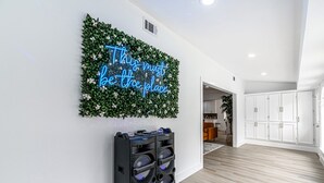 Un interior moderno con un letrero de neón en la pared, un equipo de sonido y un piso de madera.