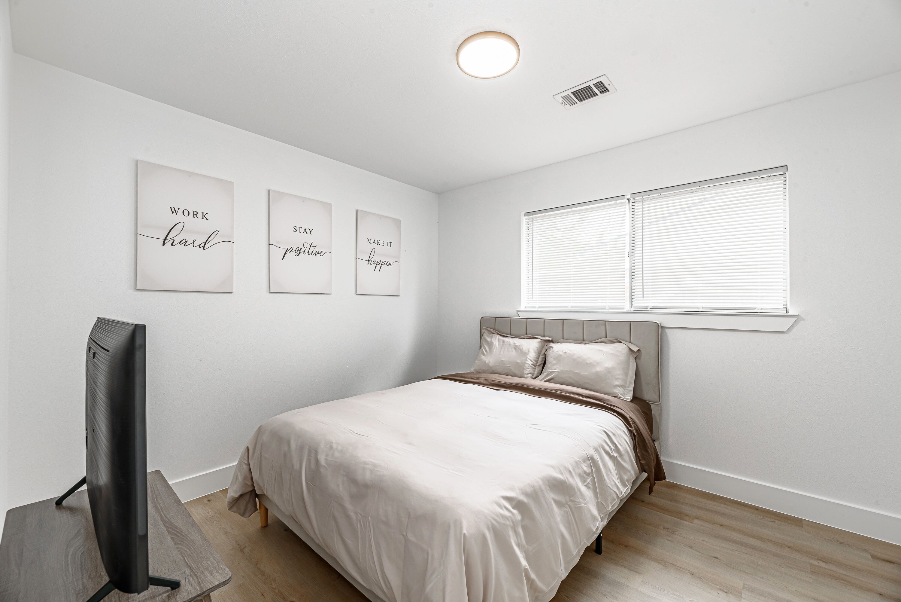 Une chambre à coucher avec un lit, un téléviseur et trois affiches inspirantes accrochées au mur.