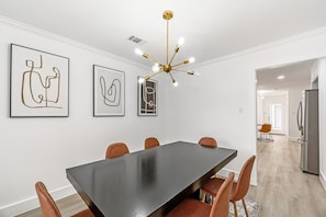 Un comedor moderno con una mesa larga, seis sillas y una lámpara de techo original.