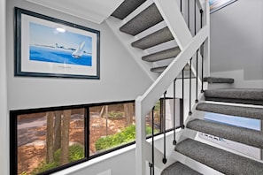 Stunning staircase with expansive views of lush outdoor landscape and a beautiful sailboat artwork.