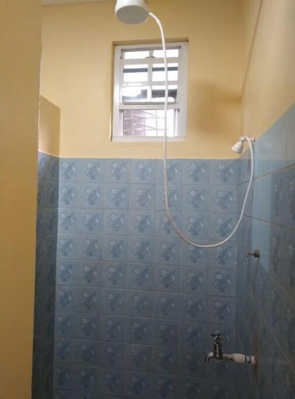 Ein kleines Badezimmer mit Dusche, Fenster und Toilette.