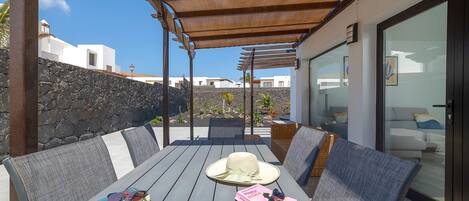 An outdoor seating area with a table, chairs, and a pergola.