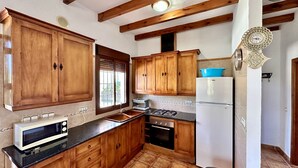 A kitchen with wooden cabinets, a stove, a microwave, and a refrigerator.