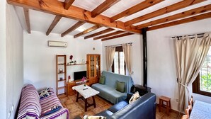A cozy living room with a wooden ceiling, a sofa, a TV, and a cabinet.