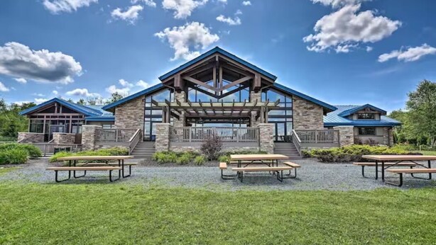 A lodge with a stone facade, a covered patio, and picnic tables in front.