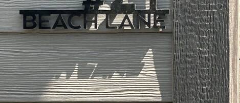 A building facade with a sign reading '21 Beach Lane' and a silhouette of a sailboat.