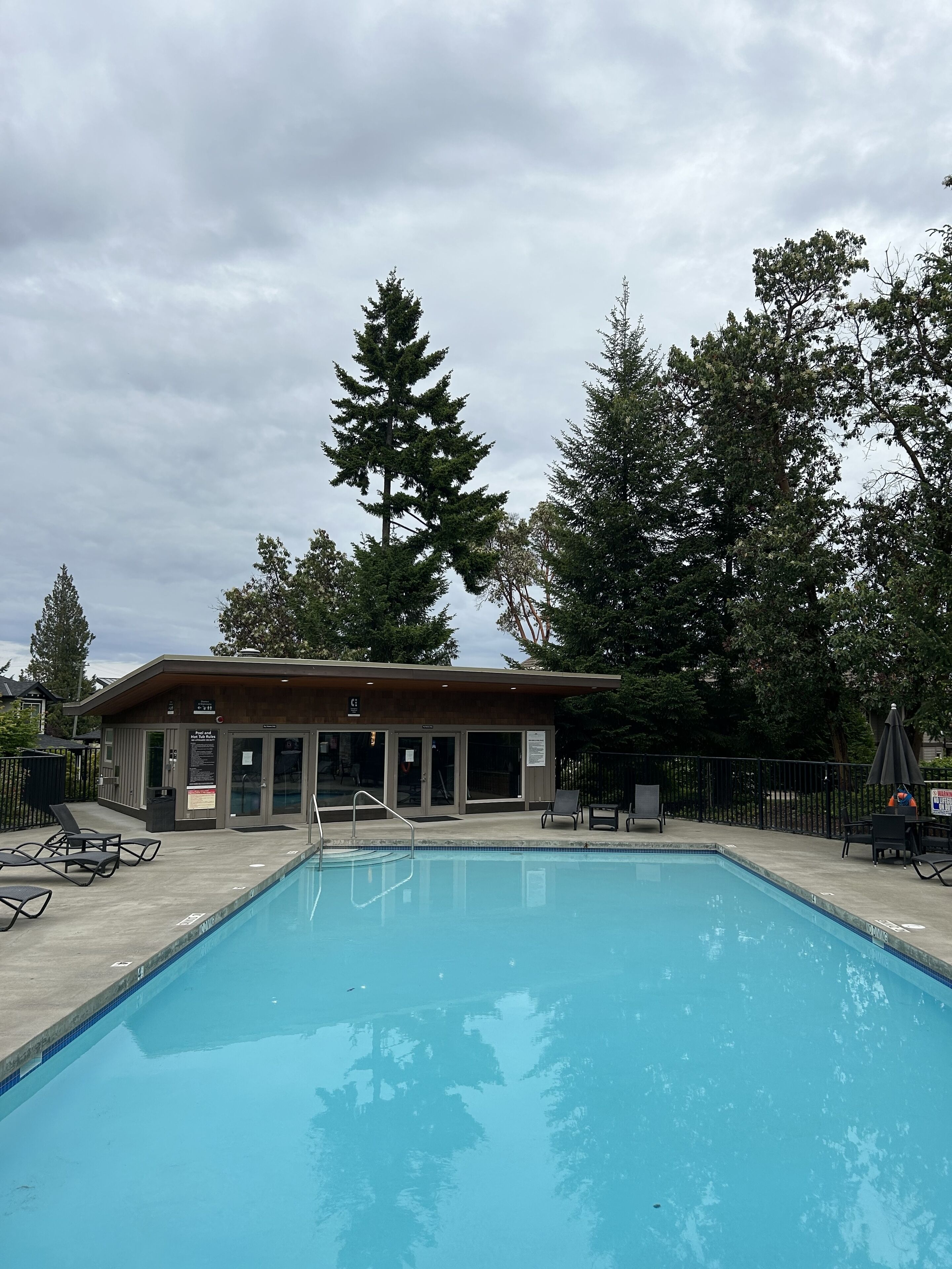 Une piscine avec des chaises longues et un bâtiment portant une enseigne.