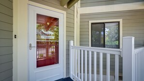 A white door with a red glass panel and a 'Welcome' sign, a white porch railing, and a window with blinds. - Serene Myrtle Beach Condo w/ Resort Amenities! (Myrtle Beach)
