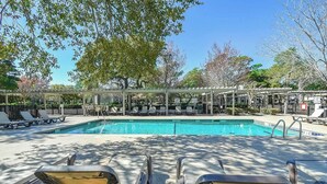 A pool area with lounge chairs and a covered seating area. - Serene Myrtle Beach Condo w/ Resort Amenities! (Myrtle Beach)
