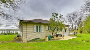 A single-story house with a front porch, a small garden, and a view of a lake. - Charming Canandaigua Lake House w/ Deck & Views! (Canandaigua)