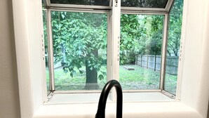A kitchen with a window overlooking a backyard. - Red Tail Cottage: Full Fence, Hammock Chair, Walk to Bass Pro, Movie Night (Springfield)