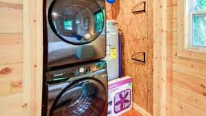 A compact laundry area with a Samsung washer and dryer, a water heater, and a fan. - Cozy Hiker's Hideaway: Steps From Creeper Trail! (Damascus)