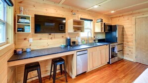 A compact kitchen with wooden walls, a countertop, a sink, a refrigerator, and a dishwasher. - Cozy Hiker's Hideaway: Steps From Creeper Trail! (Damascus)