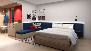 Une chambre d’hôtel moderne dotée d’un grand lit, d’un coin salon avec un canapé et des coussins, d’un bureau avec une chaise et d’une armoire.
