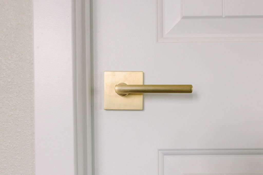Une porte blanche avec une poignée de porte en laiton et une plaque rectangulaire.