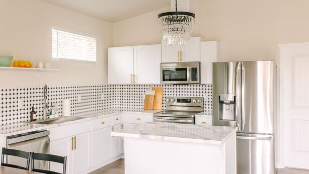 Una cocina moderna con armarios blancos, electrodomésticos de acero inoxidable y una isla central.