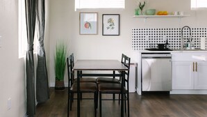Una cocina compacta con una mesa y sillas, lavavajillas integrado y una pequeña encimera con fregadero.
