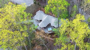 A secluded cabin with a large deck and a hot tub, surrounded by dense forest. - Foxfire Tent (Bryson City)
