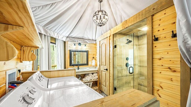 A modern, well-lit room with a wooden interior, a large bathtub, and a glass shower enclosure. - Foxfire Tent (Bryson City)