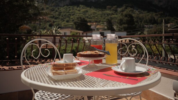 A table set for breakfast with sandwiches, a cake, and a fruit drink, overlooking a mountainous landscape. - Sikelìa Bed & Breakfast (Carini)