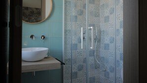 A bathroom with a white sink, a mirror, and a shower with patterned tiles. - Sikelìa Bed & Breakfast (Carini)