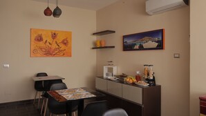 A modern kitchen with a dining area, featuring a table with chairs, a refrigerator, and a coffee machine. - Sikelìa Bed & Breakfast (Carini)