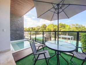 A rooftop terrace with a glass table, chairs, and an umbrella.