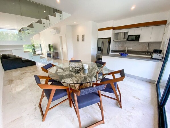 A modern kitchen with white cabinets, a stainless steel refrigerator, and a microwave.