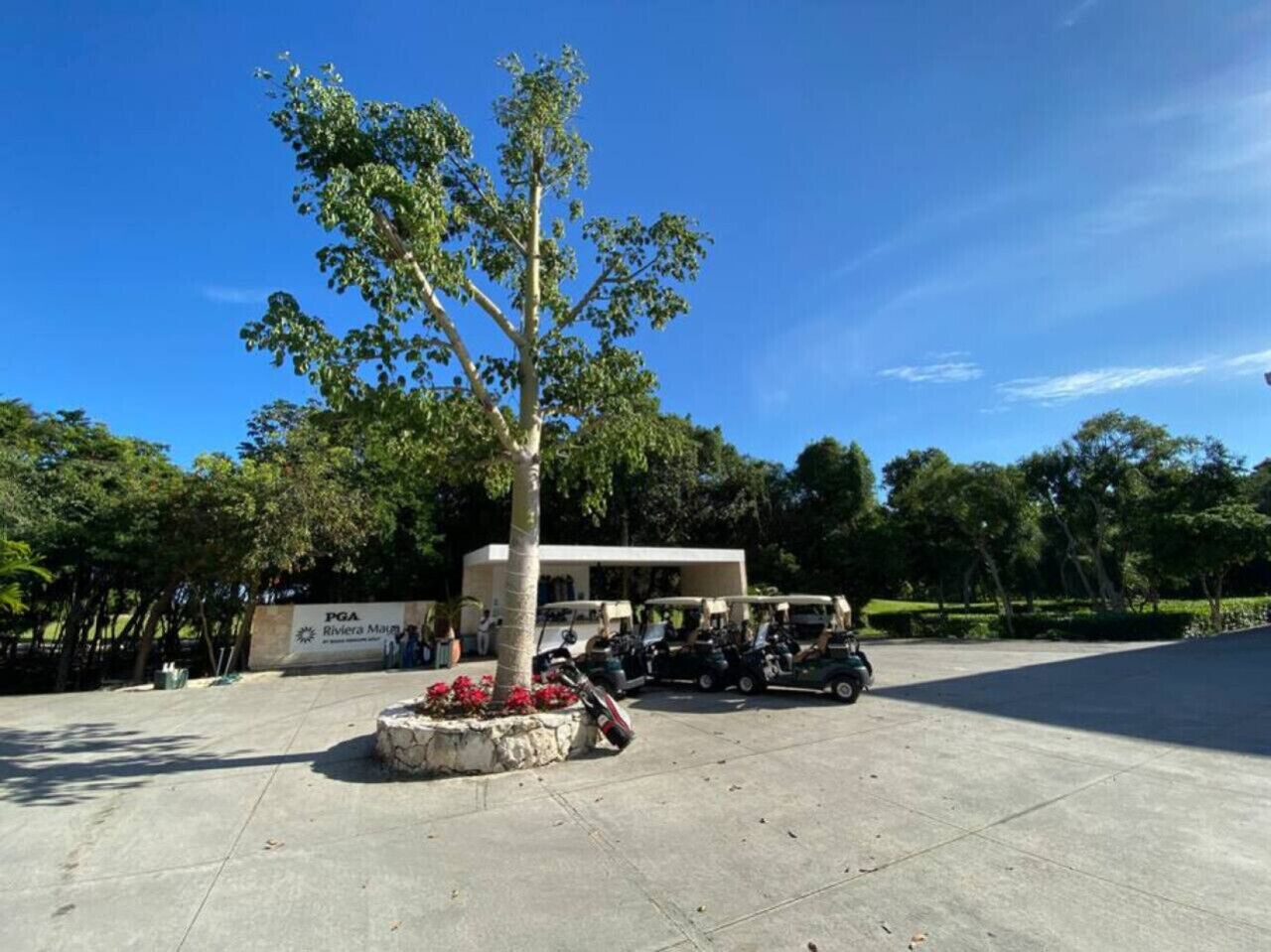 A parking area with a building labeled 'PGA Riviera Maya' and several golf carts.
