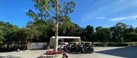 A parking area with a building labeled 'PGA Riviera Maya' and several golf carts.