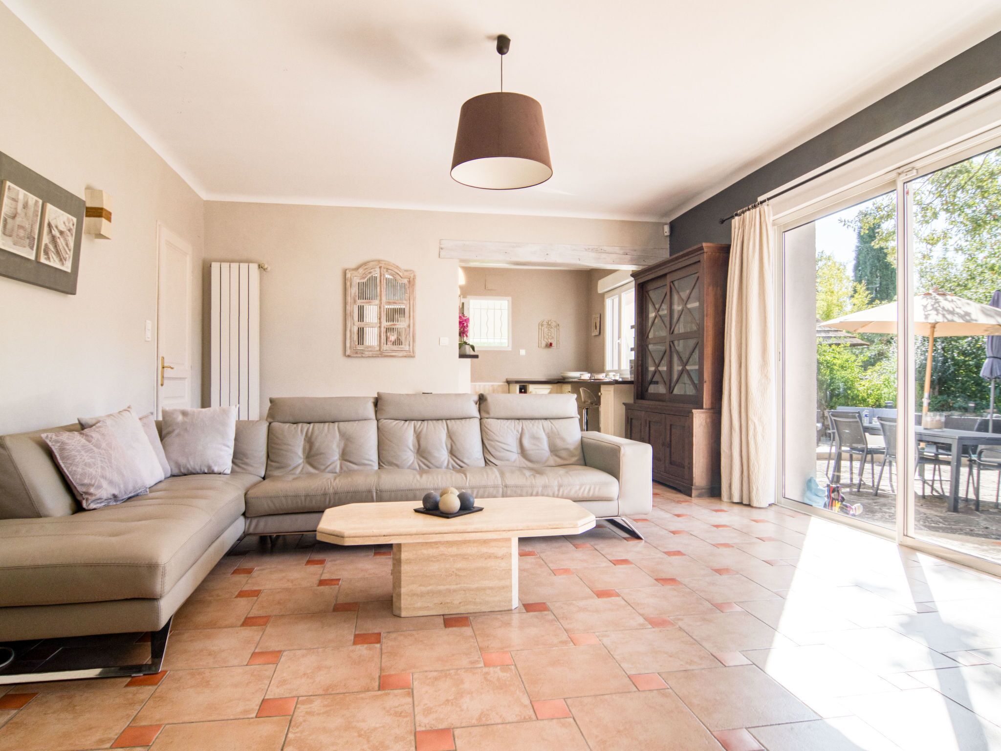 A spacious living room with a large sofa, a coffee table, and a dining area with outdoor seating.
