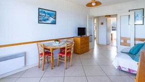 Une pièce comprenant une table à manger, des chaises, un téléviseur, un lit et un tableau accroché au mur.