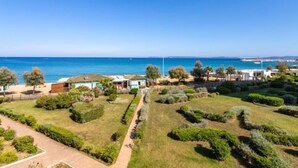 Une propriété située sur la côte, offrant une vue dégagée sur la mer, un jardin bien entretenu et un sentier menant à la plage.