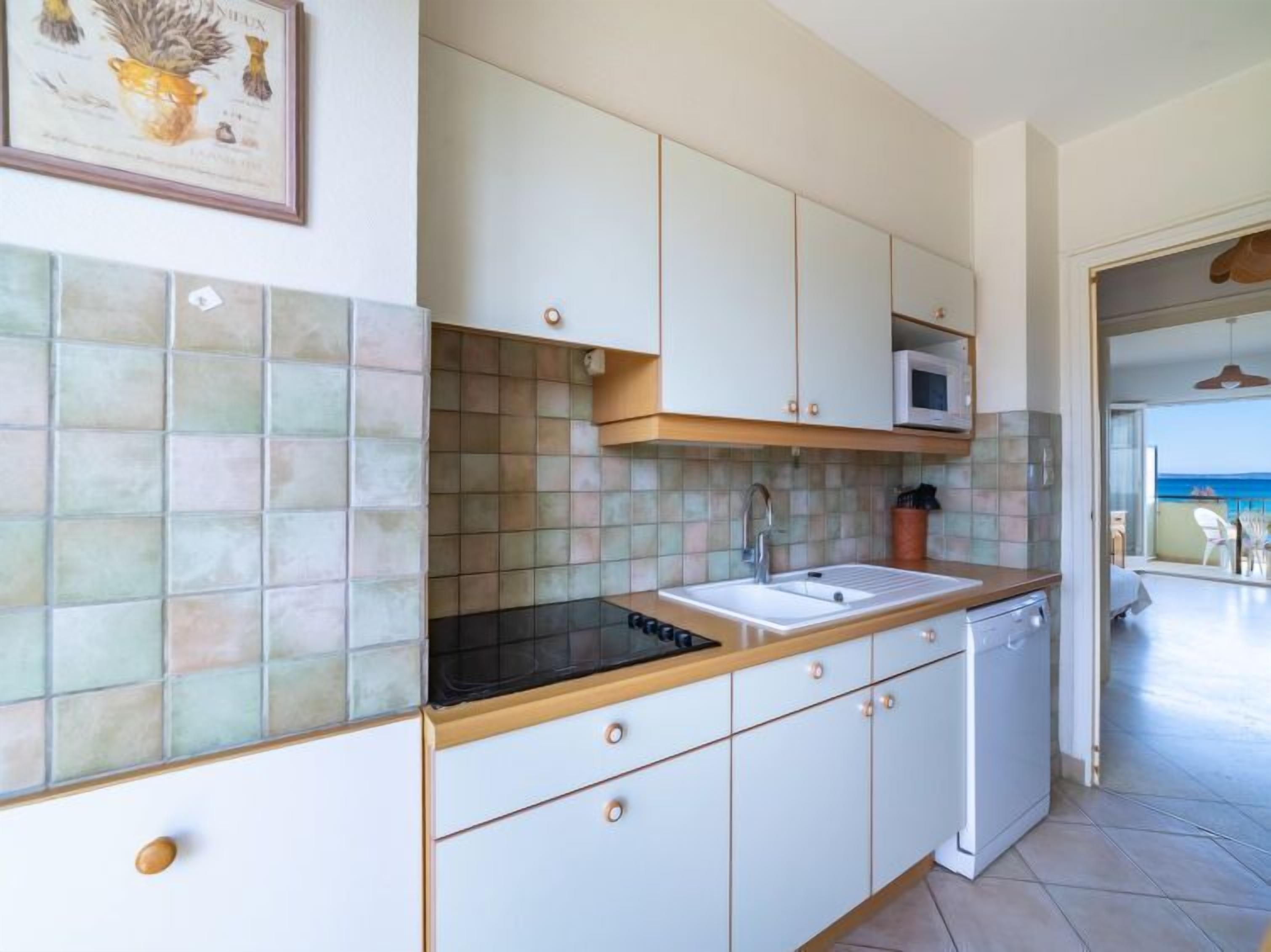 A kitchen with a tiled backsplash, a microwave, and a sink.