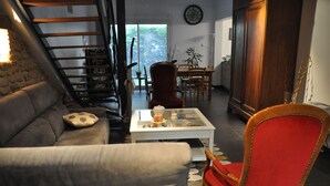 Un salon avec un canapé, un fauteuil rouge, une table basse et un escalier.