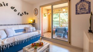 Una stanza accogliente con un letto, un tavolino con una pianta e una porta scorrevole in vetro che dà su una zona esterna con tavolo e sedie.