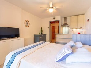 Una habitación de hotel con cama, televisión, escritorio y kitchenette.