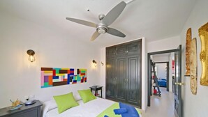 A bedroom with a bed, a ceiling fan, a colorful abstract painting, a wardrobe, and a mirror. - Mare Nostrum by Interhome (Calpe/Calp)
