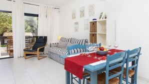 A dining area with a table set for four, a blue chair, a striped sofa, and a black chair.
