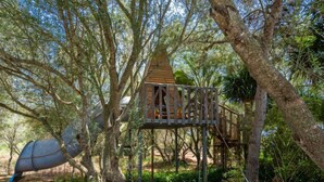 A treehouse with a wooden platform and a triangular roof, surrounded by dense foliage and trees. - Sa Caseta by Interhome (Ses Salines)