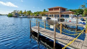 A dock with a wooden pier leading to a building with a brown roof and large windows. - Key Largo Relaxing Getaway (Key Largo)