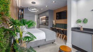 Un dormitorio moderno con cama, mesita de noche y una pequeña zona de estar.