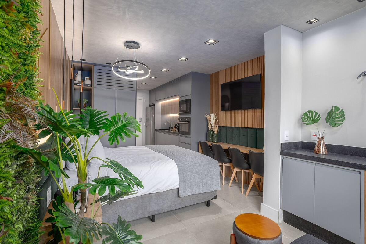 A modern bedroom with a bed, bedside table, and a small seating area.
